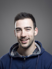 Cheerful positive young stubble man wearing blue hooded shirt looking at camera