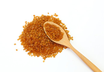 Brown caramelized sugar in a spoon against pile of brown caramelized sugar