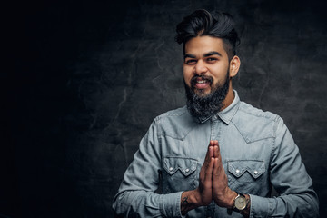 Indian man in a blue shirt over grey background.
