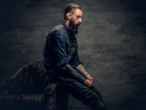 Bearded male sits on a chair.