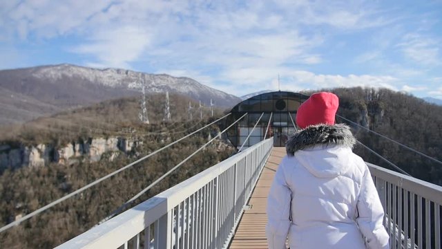 Woman walk thru high bridge over the canyon at SkyPark AJ Hackett Sochi
