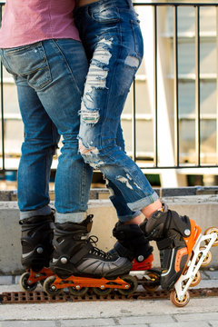 Legs of couple wearing rollerblades. Man with woman in jeans. Style and sport.