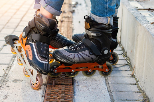 Feet on rollerblades. Orange and black inline skates. High durability and new design.
