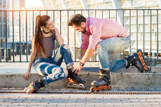 Young couple is wearing rollerblades. Man and woman smiling. In mood for a ride.