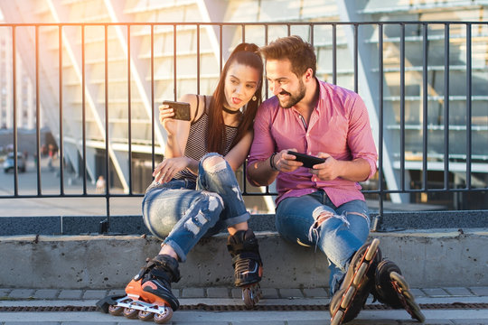 Young couple holding phones. Girl showing tongue. Take a funny selfie.