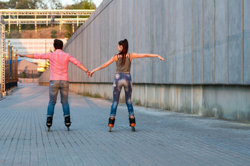 Couple on rollerblades holding hands. Back view of inline skaters. Be free like birds.