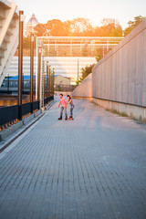 Couple of inline skaters. Two people on wide pavement. Learning to roller skate.