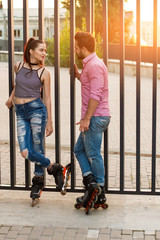 Couple on inline skates standing. Young woman looking at man. Date of active people.