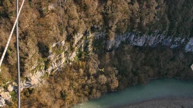 A long-shot of a unidentified man bungy jump off 207 m a steel suspension bridge