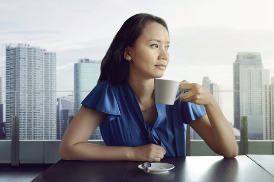 Attractive asian woman enjoying relaxing time while drinking coffee