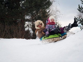 Happy kids riding a roller coaster on the tubing. Winter, snow