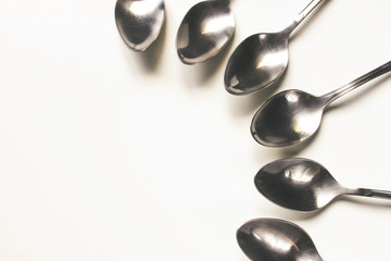 Set of table spoons is laid out on a white table 