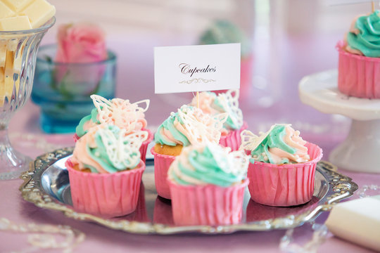 Vanilla cupcakes with pink frosting and glittery butterflies, over dot background. Fun!