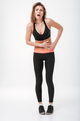 Fototapeta na wymiar Sad young fitness lady with painful holding belly