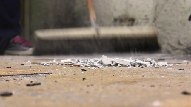 Broom Sweeping across dusty unfinished basement floor