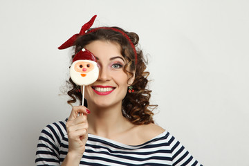 Girl pin-up posing with candy in his hand in the studio.