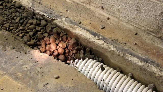 Contractor shines flashlight on interior french drain