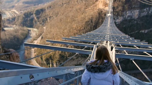 Woman walk thru high bridge over the canyon at SkyPark AJ Hackett Sochi