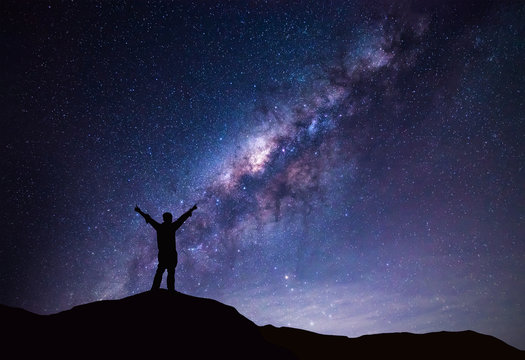 Milky Way landscape. Silhouette of Happy man standing on top of