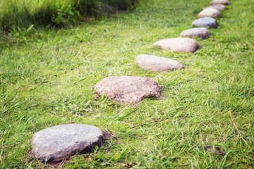 Way from  cobble-stones on green herbs a background