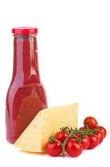 Fresh tomatoes, piece of cheese and bottle with  cowberry sauce