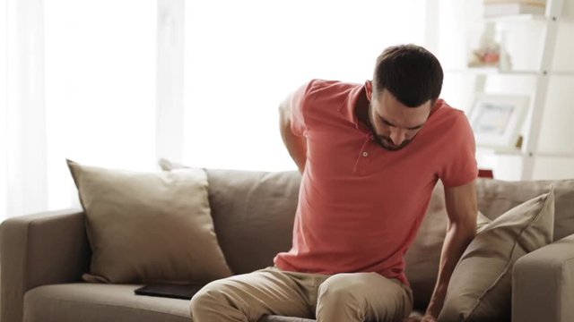 unhappy man suffering from backache at home