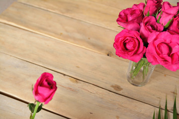 red rose in glass on wooden table