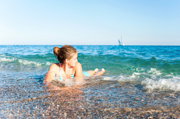 Happy young girl enjoying in sea splashing waves. Mediterranean