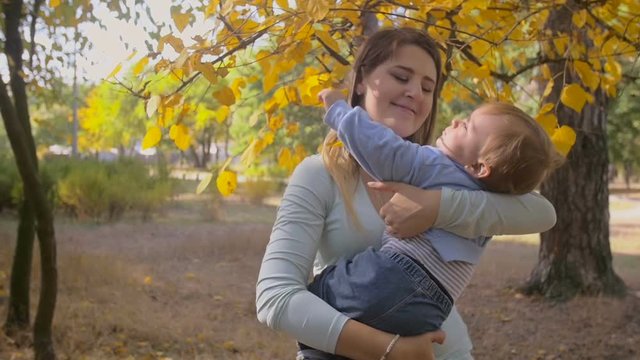 Slow motion footage of young mother holding and hugging her baby son at autumn park