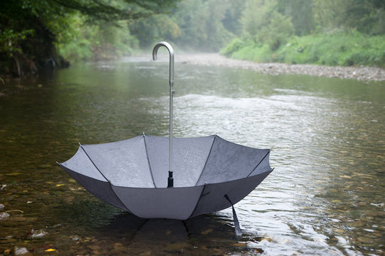 Grauer Regenschirm schwimmt im Wasser