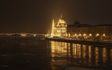 Naklejka premium Parliament at nighttime with icy Danube
