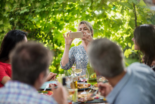 A woman takes a picture of her friends lunching on a terrace