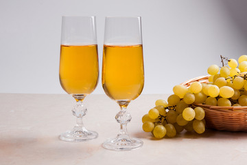 White wine and grapes. White wine in glasses and grapes on light