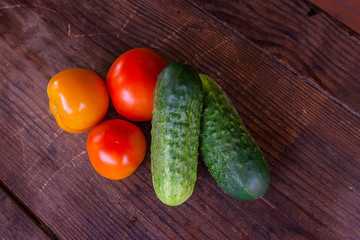 Close up view of fresh, ripe tomatoes and cucumbers on wood back