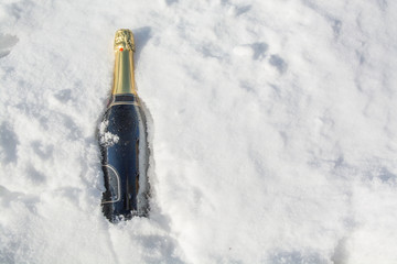 Bottle of champagne is lying in snow.