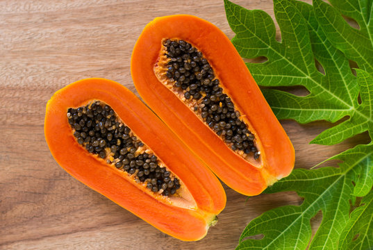 Papaya fruit on wooden background.Slices of sweet papaya on wooden background,Halved papayas with leaves,