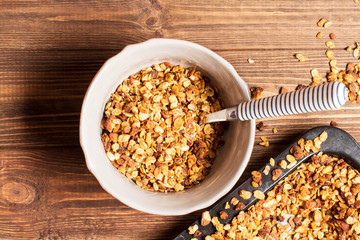 Granola in a pan on a wooden brown background, horizontal, soft focus