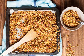 Granola in a pan on a wooden brown background, horizontal, soft focus