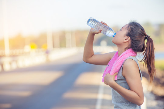 portrait of young woman drinking water after sporting