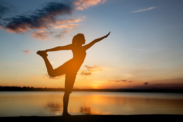 Fototapeta premium Silhouette woman with yoga posture at sunset.