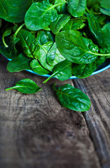 Spinach leaves in a bowl on rustic wooden table close up with co