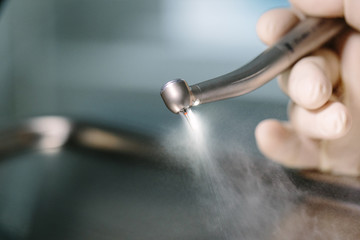 Doctor holding a dental drill tool atomizes spray the water and air by hand with protective gloves....