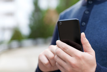 man holding black touch phone in the street