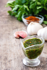 Green Chimichurri Sauce and ingredients on wooden table
