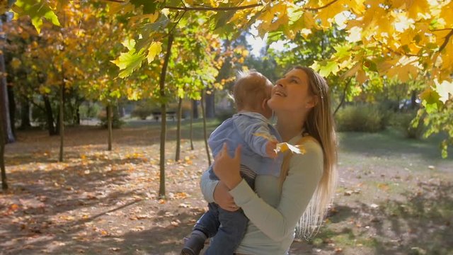 Slow motion closeup footage of mother and baby son looking at tree in autumn park
