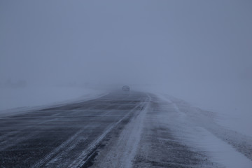 Car on winter road in a snowstorm and bad visibility