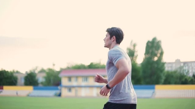 Young attractive man running on athletics running track on stadium