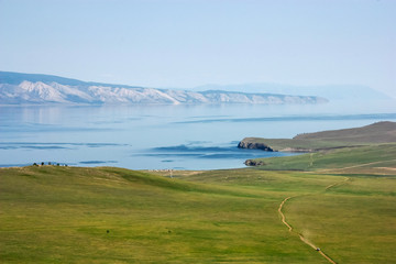 Field of green grass with road along coastline © Aniland