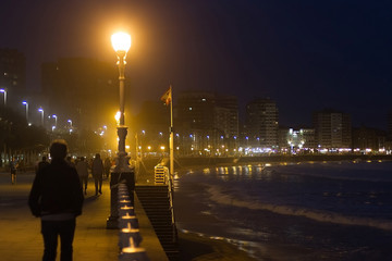 Paseo con gente al lado de la playa por la noche. Gijon. Asturias. España