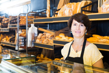 Fototapeta na wymiar middle-aged female baker with fresh bread in bakery
